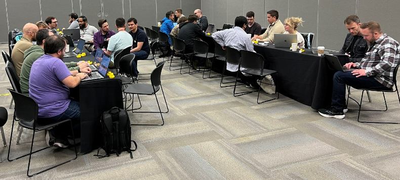People sitting at tables with computers at a software consulting conference